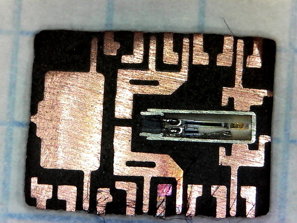 The underside of the chip's interior. Several large copper pads are visible, as is the internal 32,768 Hz crystal which has been cross-sectioned due to excessive sanding.